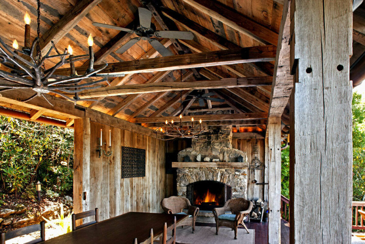Rustic reclaimed hand hewn wood beams around outdoor fireplace and dining room.