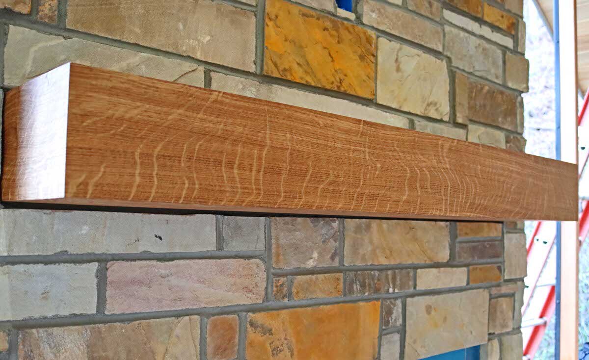 oak box mantel with wood rays against a brick Box fireplace