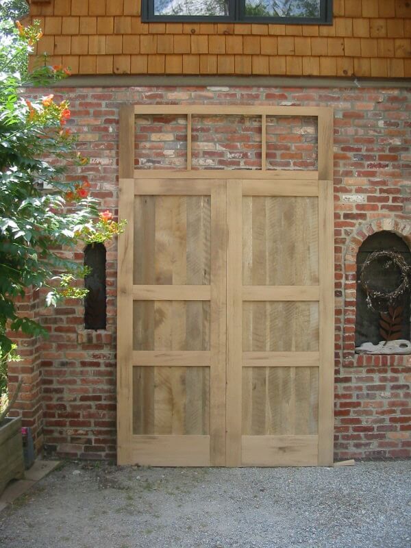 Reclaimed oak double doors with unfinished transom against a brick wall