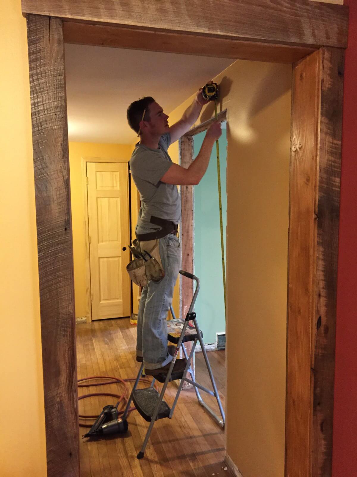 man on ladder installing Reclaimed trim around a door in asheville, nc cottage