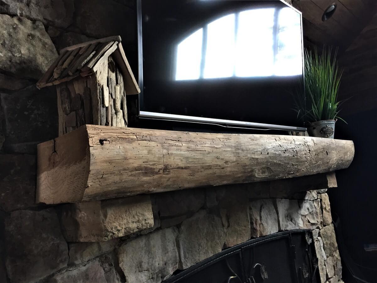 Unfinished live edge wood mantel above stone fireplace near lake toxaway nc
